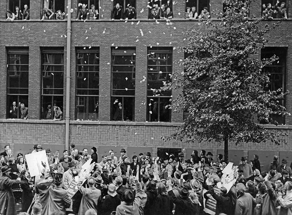 Frits Philips (here waving from the window), who remained in the Netherlands, is the centerpiece of an impromptu Philips folk festival during the war | © Philips Company Archives