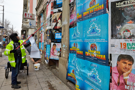 Een stadmedewerker is bezig met het plakken van posters.